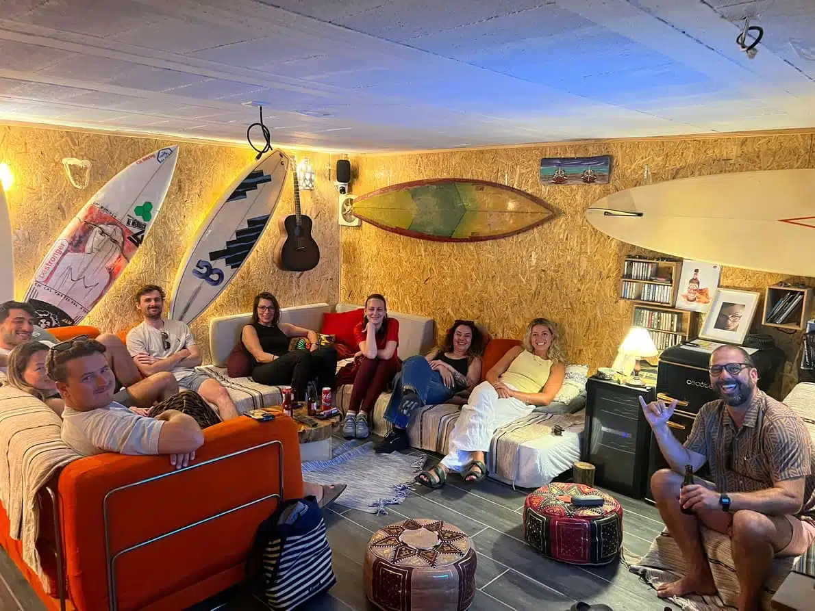 Sea Krew Collective community gathering in surf lounge with surfboards on walls, Ericeira Portugal