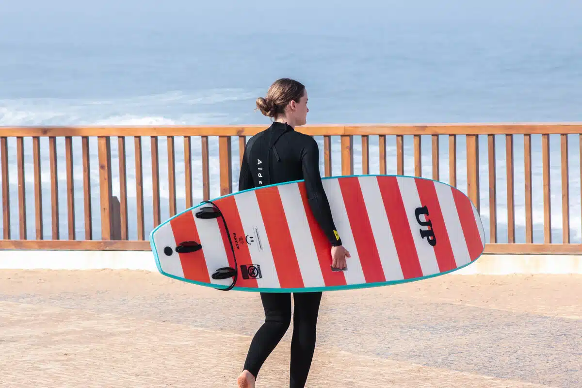 Woman carrying surf board in Ericeira – Sea Krew surf lessons Portugal