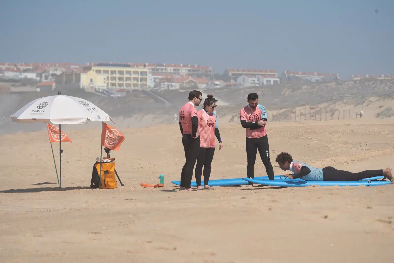 Beginner practising the surf pop-up on the sand during a lesson in Ericeira, Portugal