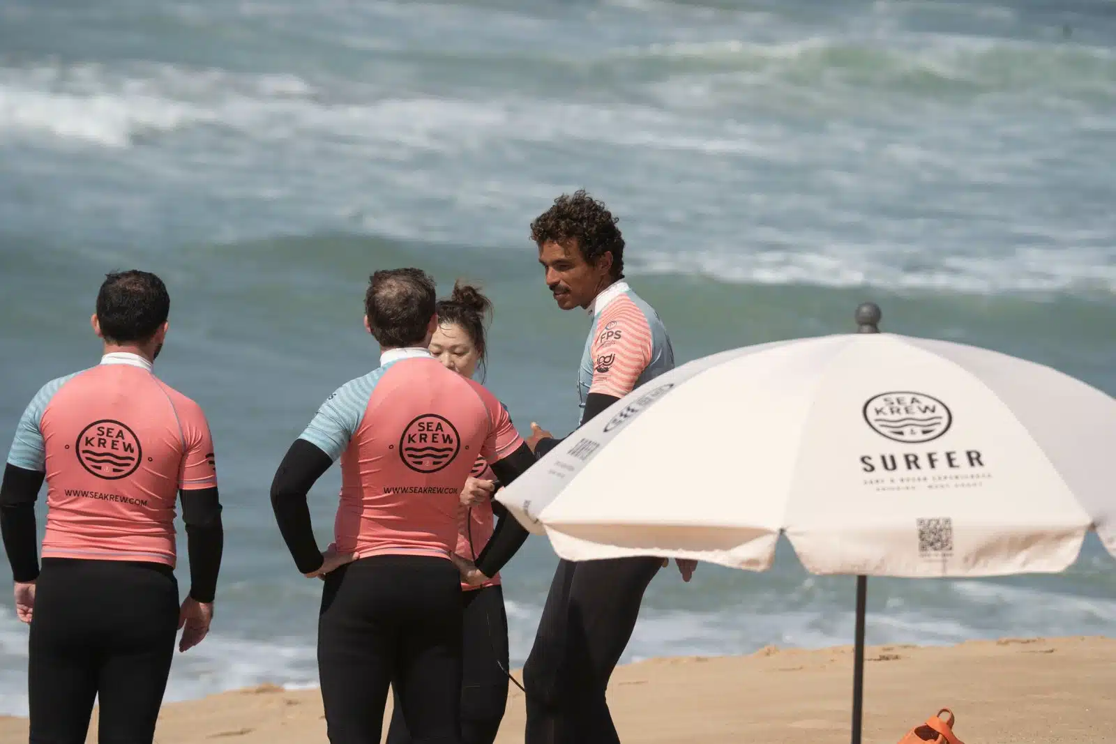 Sea Krew surf club community chatting with the coach on the beach in Ericeira