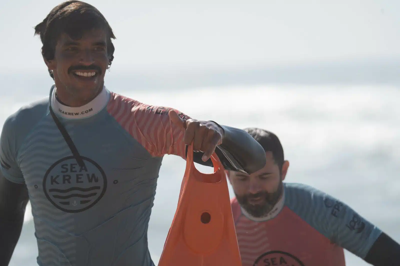 Sea Krew surf coach and beginner student laughing together after a surf lesson in Ericeira