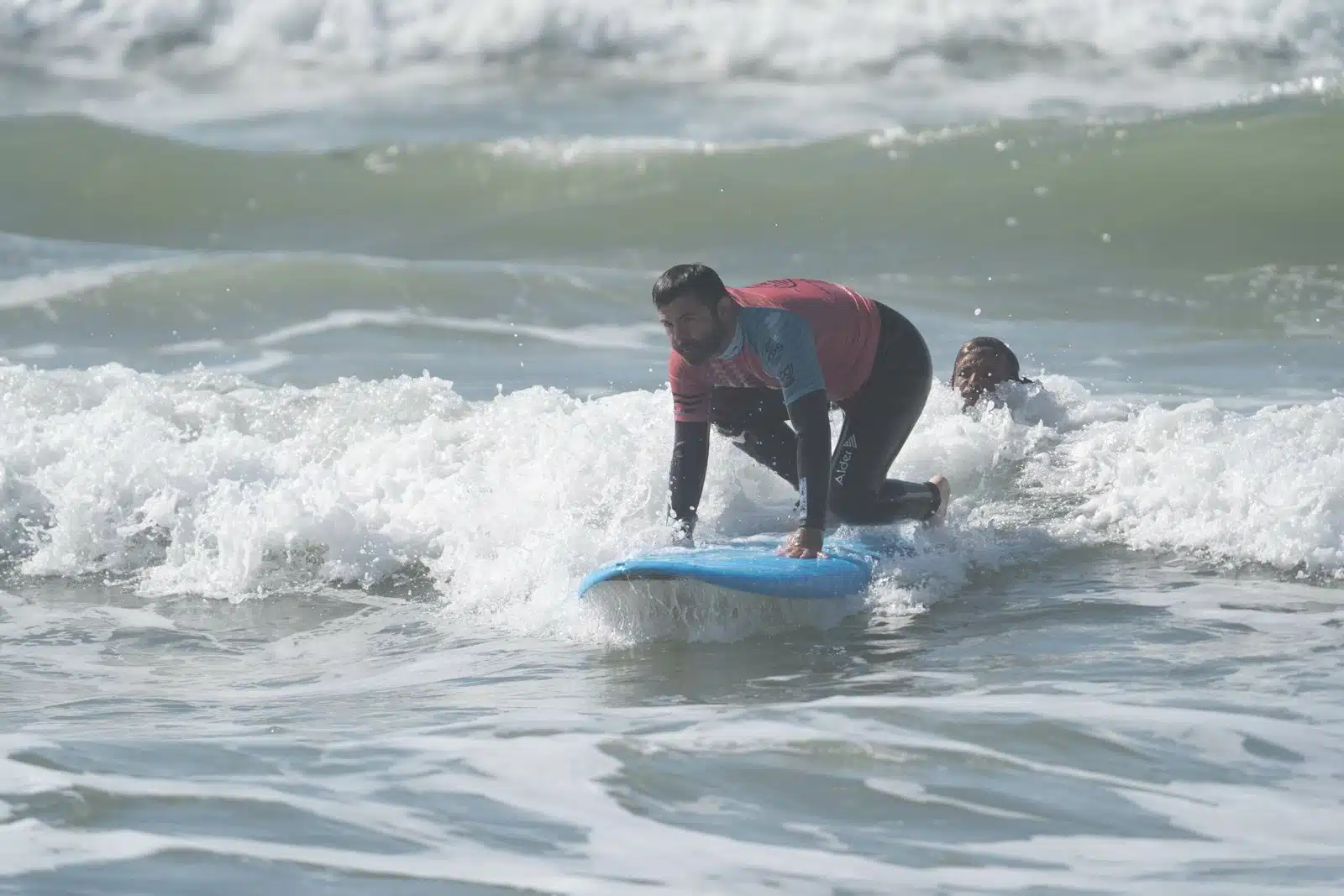 Beginner surfer riding his first whitewater wave on a soft-top board in Ericeira